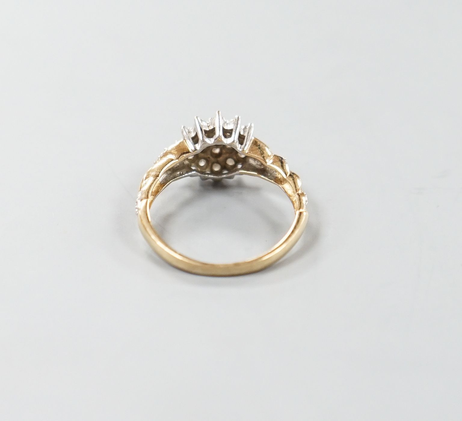 A modern 9ct gold and diamond cluster ring, with diamond chip set shoulders, size P, gross weight 2.5 grams.